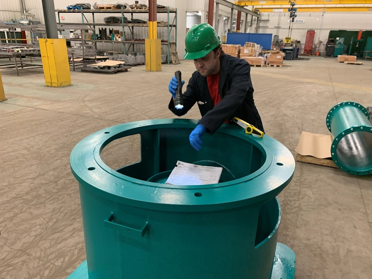 Man with flashlight inspecting coating on pipe