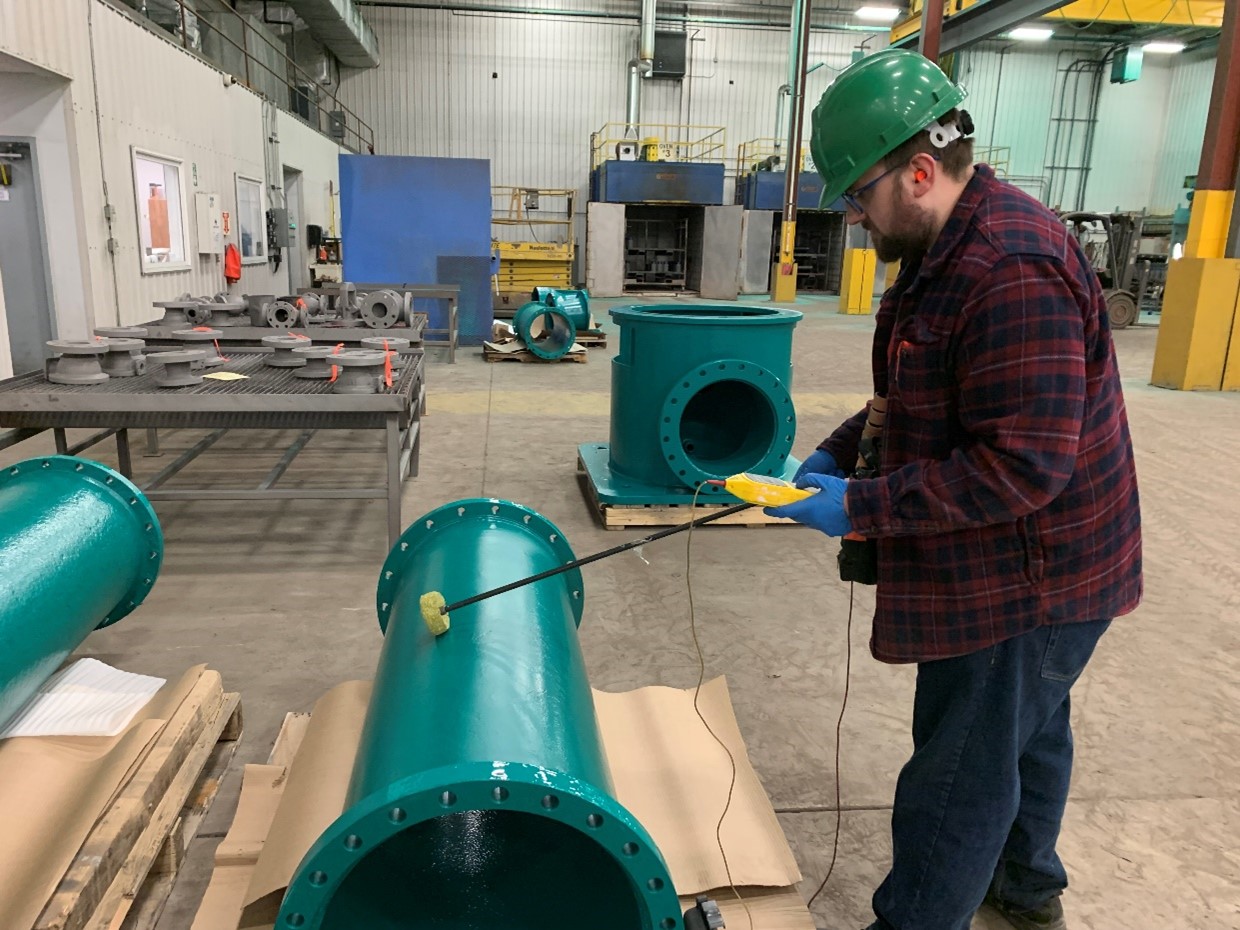 Man standing beside pipe freshly coating in Scotchkote 134