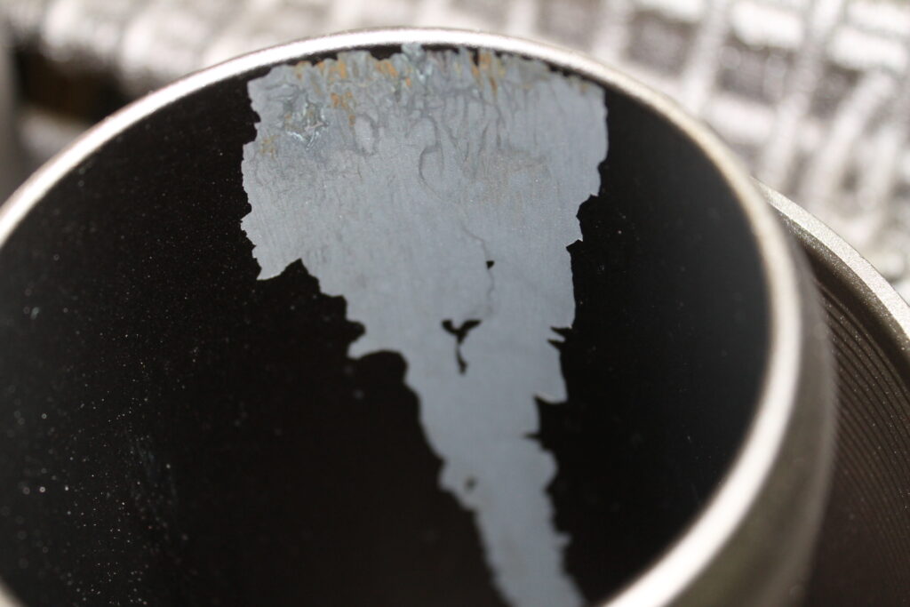 The inside of a pipe is showing signs of flaking and needs a reapplication or maintenance.
